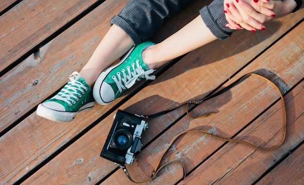 Close-up shot of a person's feet wearing retro runner sneakers, highlighting the details of the shoe, such as the stitching, materials, and color scheme. The background should be blurred to keep the focus on the footwear.