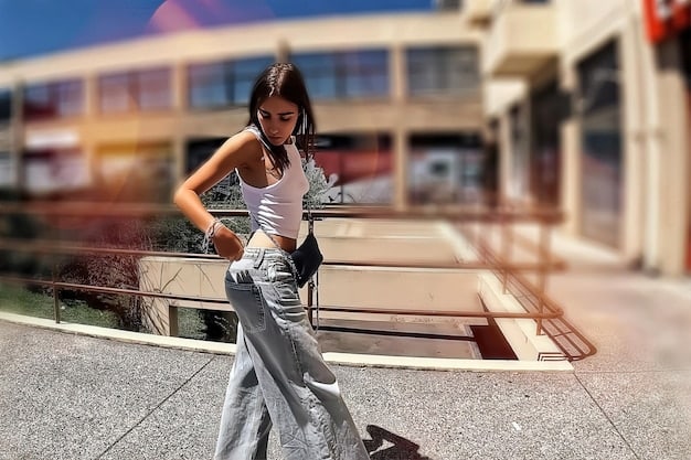 A person with an inverted triangle body type wearing a streetwear outfit consisting of a V-neck top, wide-leg pants, and sneakers. The setting is a modern urban environment.