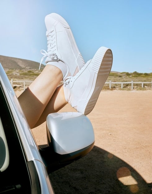 A close-up shot of a woman's feet wearing retro-inspired sneakers with a chunky sole, styled with high-waisted jeans and an oversized bomber jacket. The sneakers feature a neutral colorway with subtle pops of color, showcasing the stylish blend of vintage and modern elements.