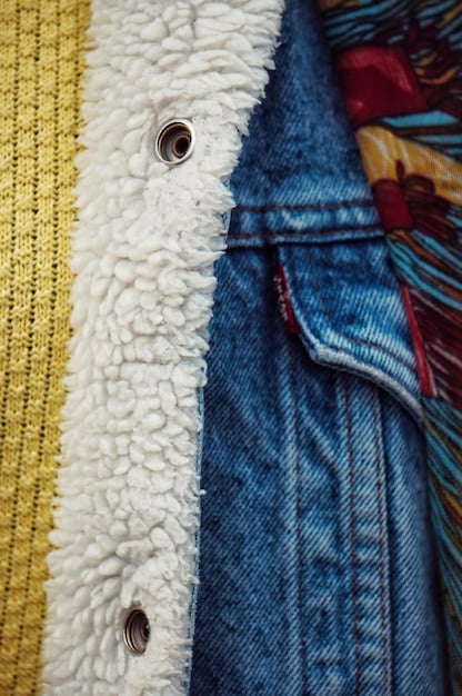 A close-up shot of layered clothing textures, including denim, cotton, and fleece, showcasing the different materials and their interplay in a streetwear outfit.