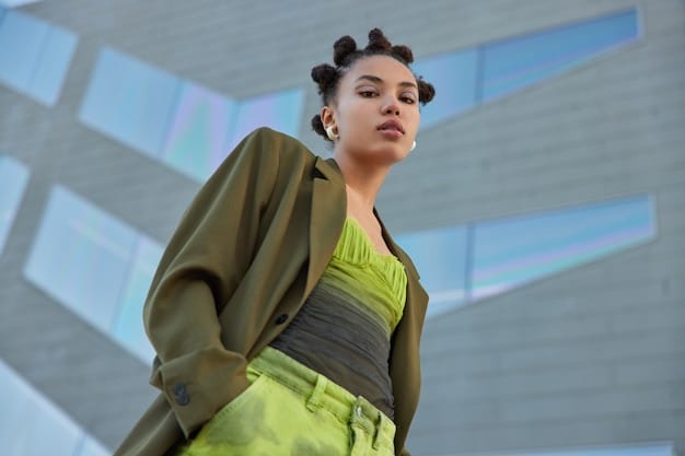 A close-up shot of a woman wearing a chic streetwear outfit in various shades of gray. She is wearing a light gray wool coat over a charcoal gray turtleneck sweater, paired with medium gray wide-leg pants. Her sneakers have subtle neon green accents.