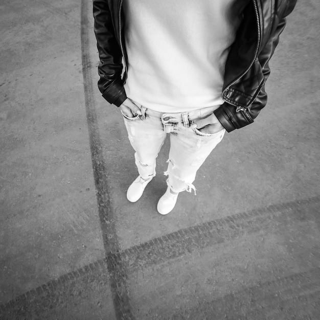 A close-up shot of layered streetwear items: a basic white tee, a black hoodie, a denim jacket, and a pair of stylish sneakers. The background is a clean, minimalist studio setting.