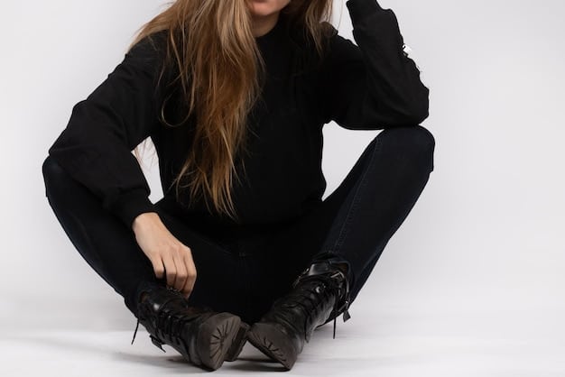 A close-up shot of black leather ankle boots with a chunky sole, paired with ripped jeans and an oversized hoodie, showcasing a classic streetwear look with a touch of edginess.