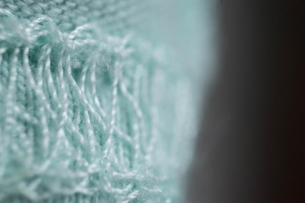 Close-up shot of a textured textile in muted teal, showcasing its subtle variations in tone and depth, with soft lighting highlighting the fabric's weave.