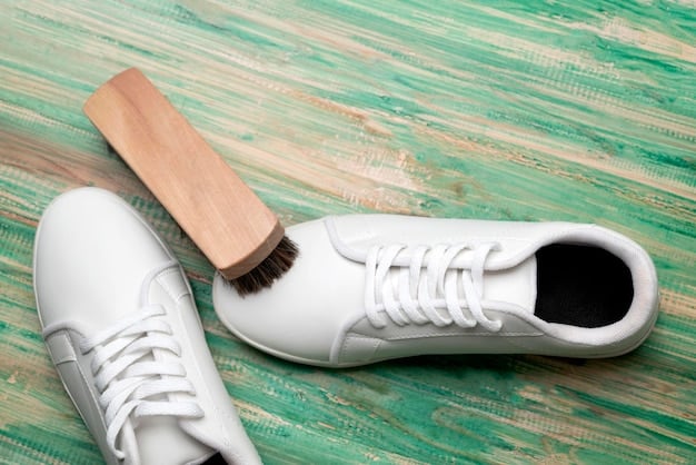 A person is carefully cleaning a pair of white leather sneakers with a soft brush and cleaning solution, with various cleaning supplies arranged neatly on a table.