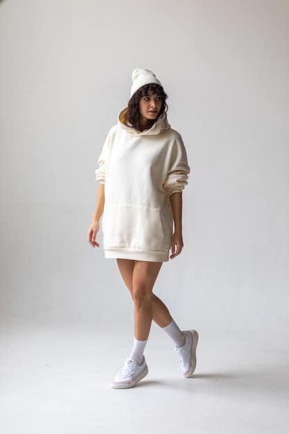 A woman wearing a monochromatic outfit consisting of an oversized cream hoodie, matching relaxed-fit wide-leg trousers, and cream chunky sneakers, holding a simple beige cross-body bag, showcasing a sleek and unified streetwear aesthetic.