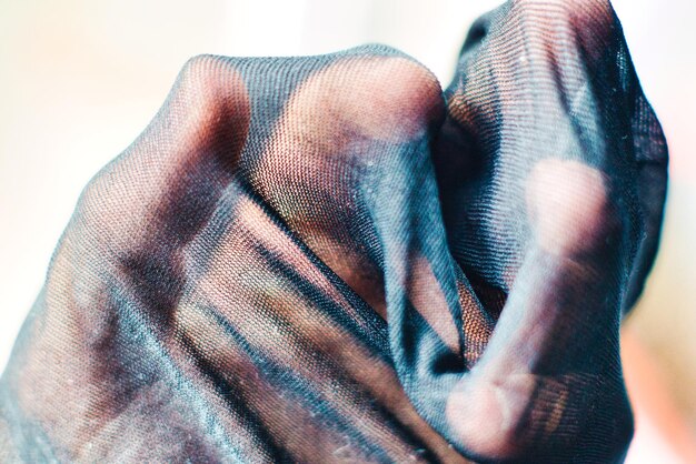 A close-up shot focusing on the texture of layered fabrics. One arm is showcasing a soft knit sweater over a crisp cotton shirt, topped with a sleek leather jacket, highlighting the contrast and harmony of materials.